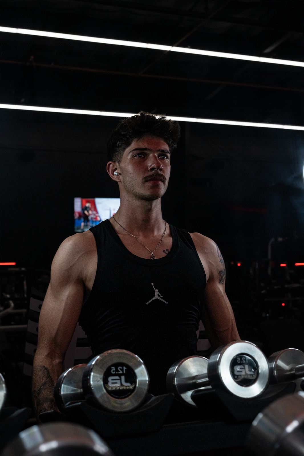 Athlete training with dumbbells in a dark gym
